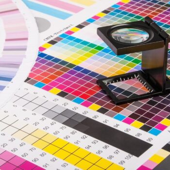 Magnifying glass examining color test print on NUtec Digital Ink's color charts, highlighting printing quality and color accuracy for digital printing inks